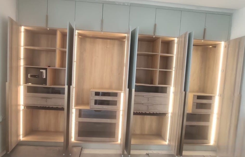 Custom hinged wardrobe with internal LED strip lighting and modular shelves by SB Interior Solutions Hyderabad