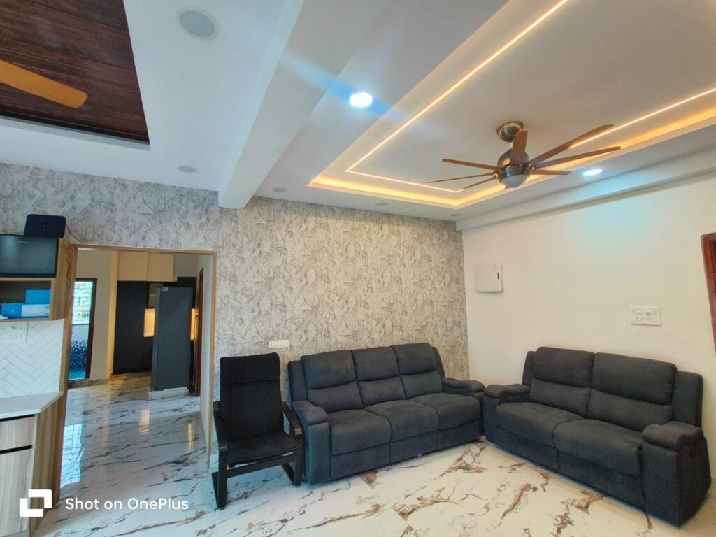 Living room interior with false ceiling, LED cove lighting and grey sofa set by SB Interior Solutions Hyderabad